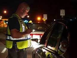 An officer holds a flashlight while checking the driver's license of a motorist at a DUI checkpoint