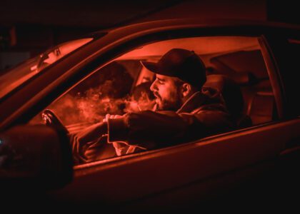 Man smoking while sitting in driver's seat of car, which shouldn't be done with marijuana in Oklahoma