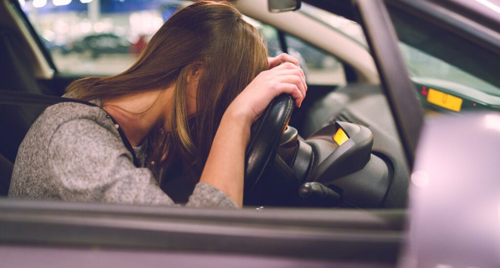 A women is slumped over the steering wheel as though she is in actual physical control while under the influence